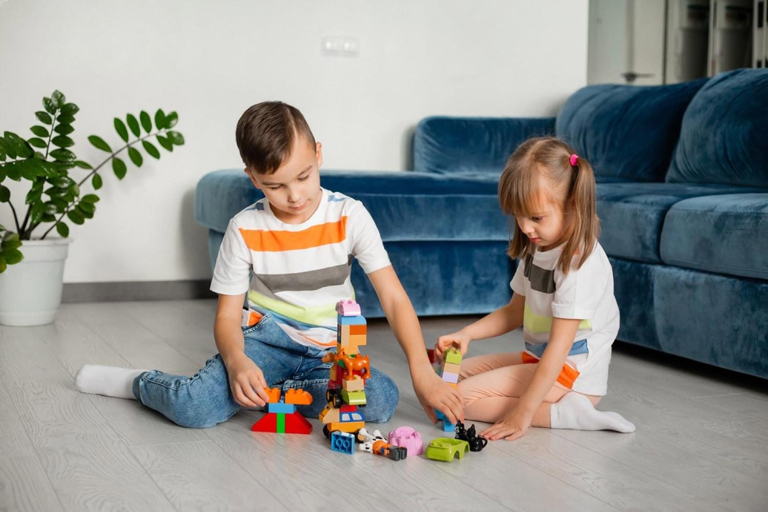 Two young children building with colourful construction blocks on the floor